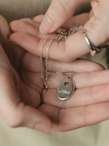 Silver engraved necklace with cognac amber shown on the hand