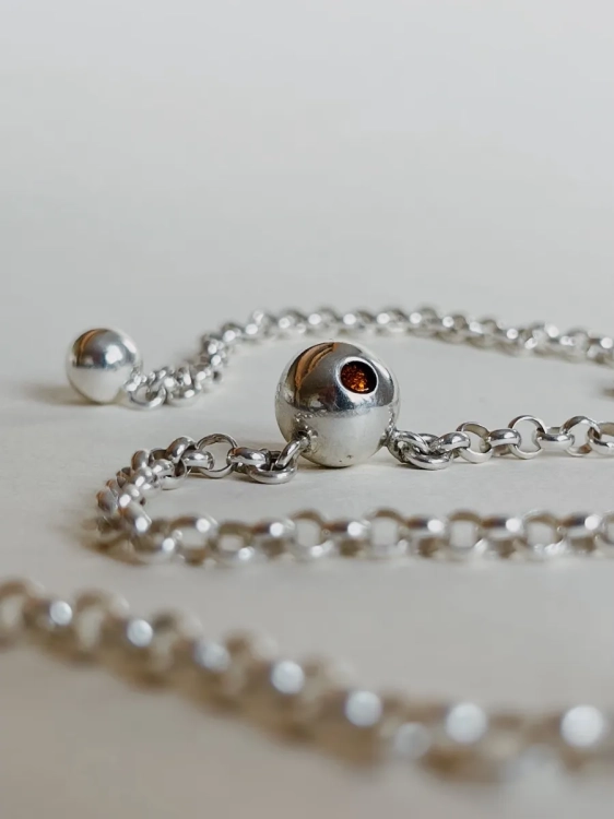 Sterling silver chain necklace with amber-inlaid sphere, close-up