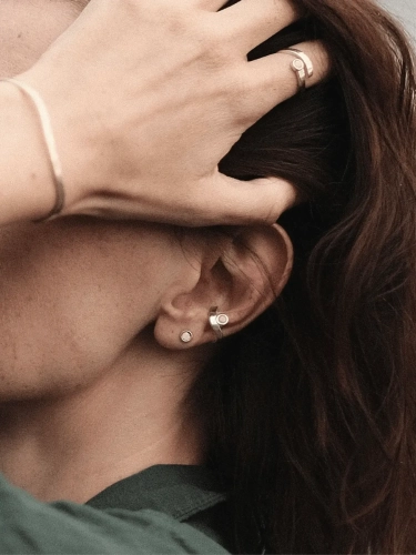 Silver stud earrings with milky amber worn on the ear
