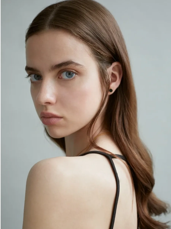 Gold-plated stud earrings with black flint worn on the ear